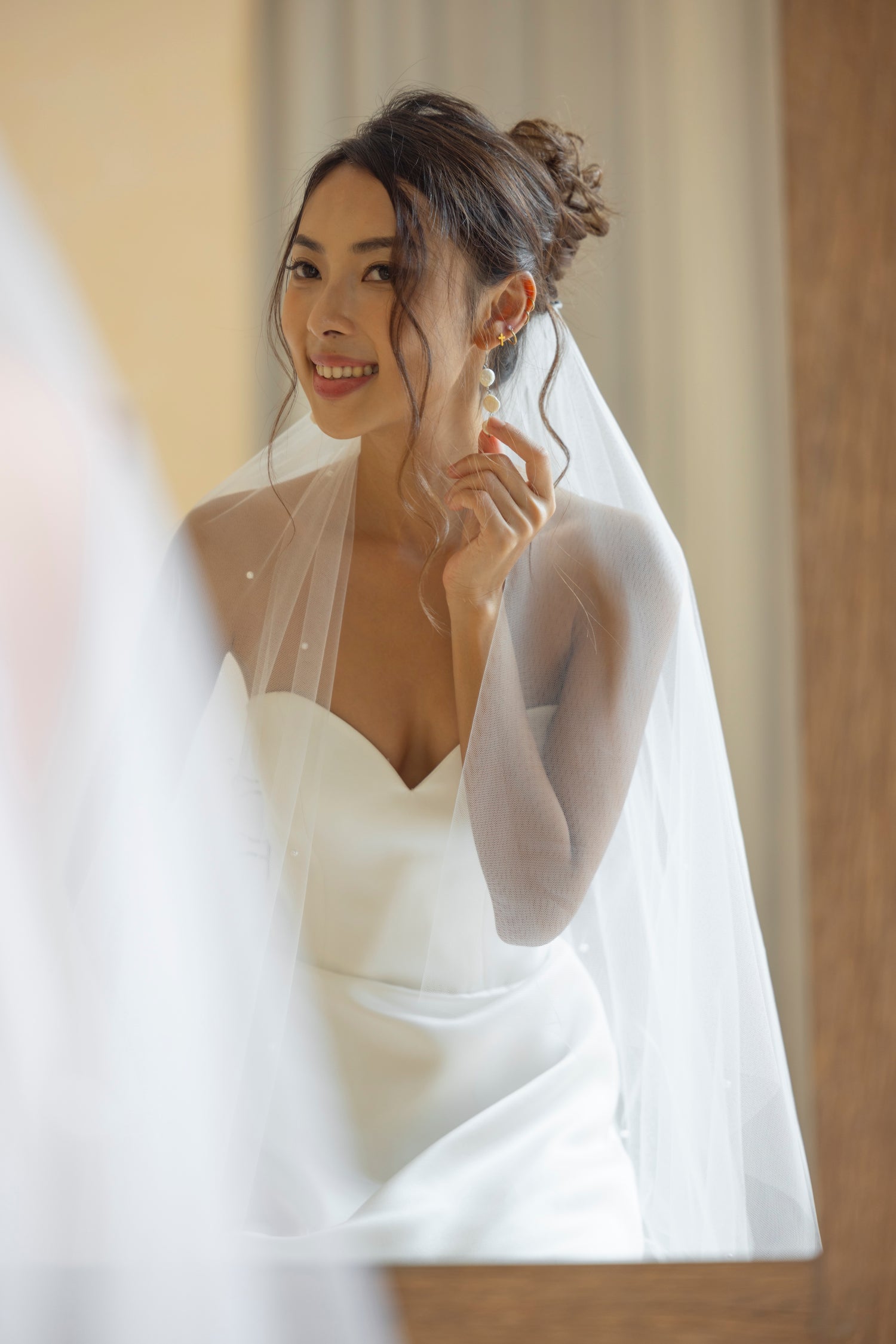 Close-up of pearl veil and earrings. A soft-focus moment capturing delicate bridal details with effortless, romantic charm.