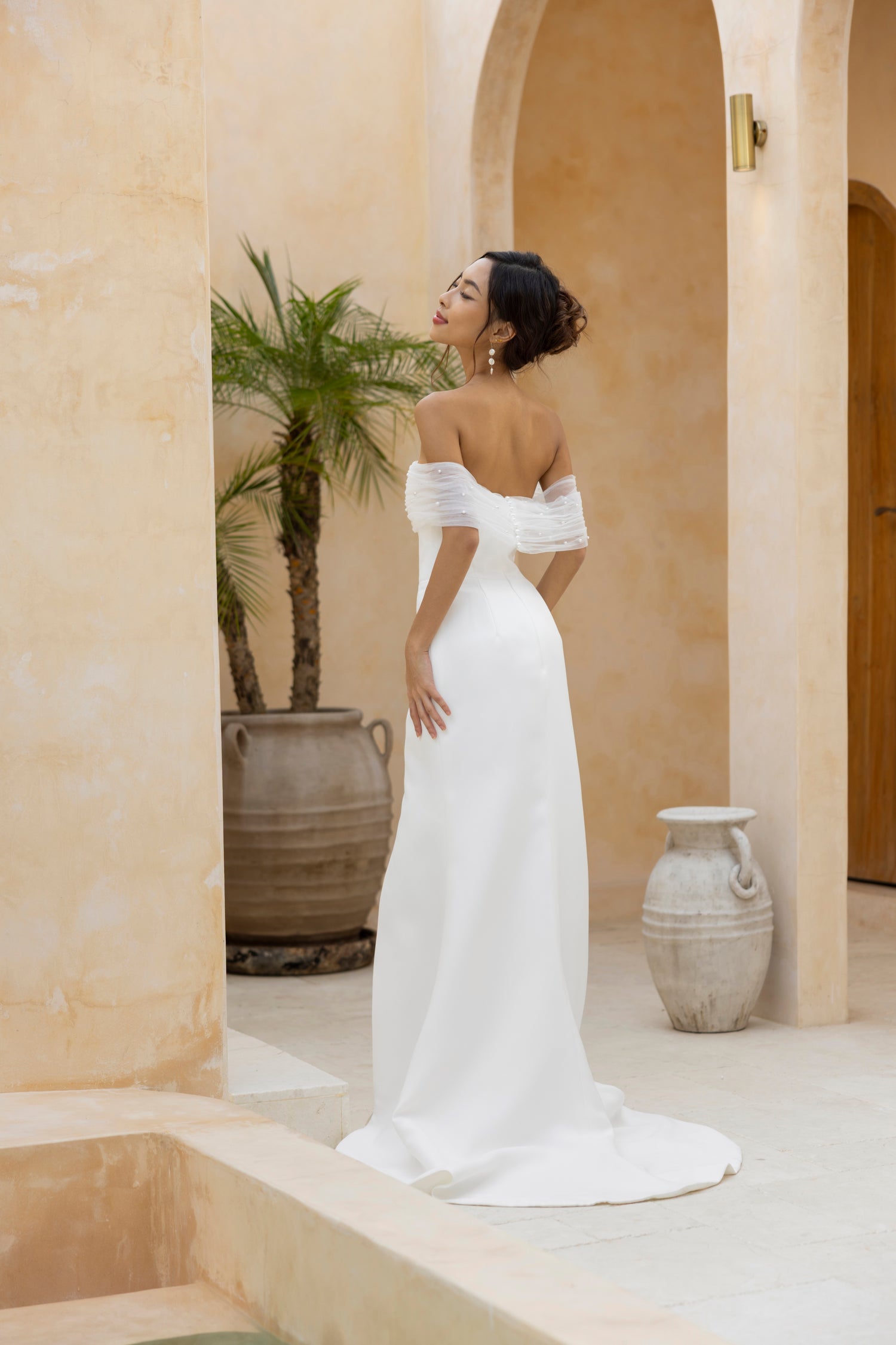 Back view of TheWolfandLily’s Teagan gown with a detachable pearl-embellished tulle wrap.