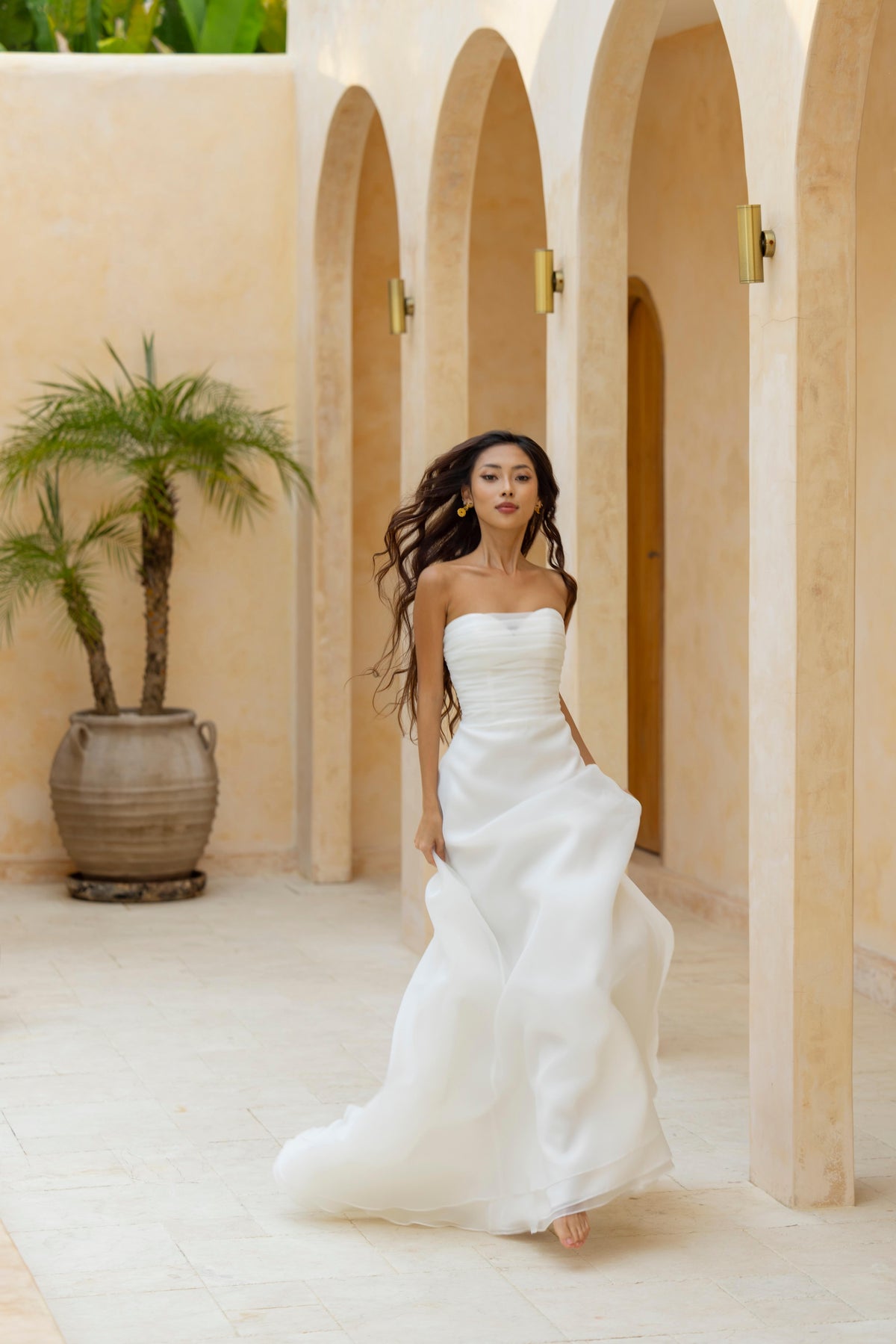 Bride twirls in the Charlie sleeveless dress by The Wolf and The Lily, showcasing movement of lightweight organza skirt.