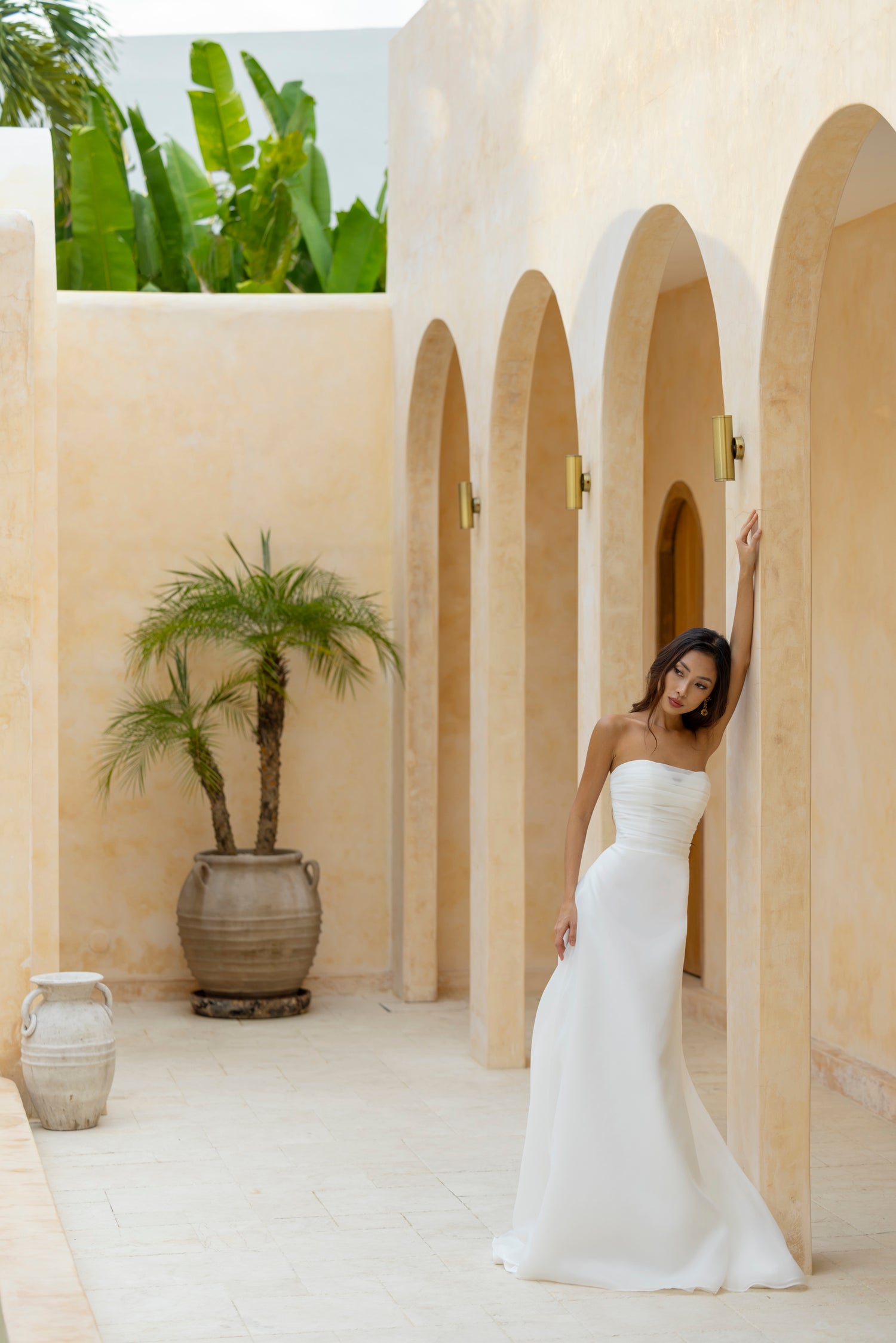 Minimalist bride wears the Charlie gown by The Wolf and The Lily, a sleek strapless wedding dress with ruched detailing and no sleeves.