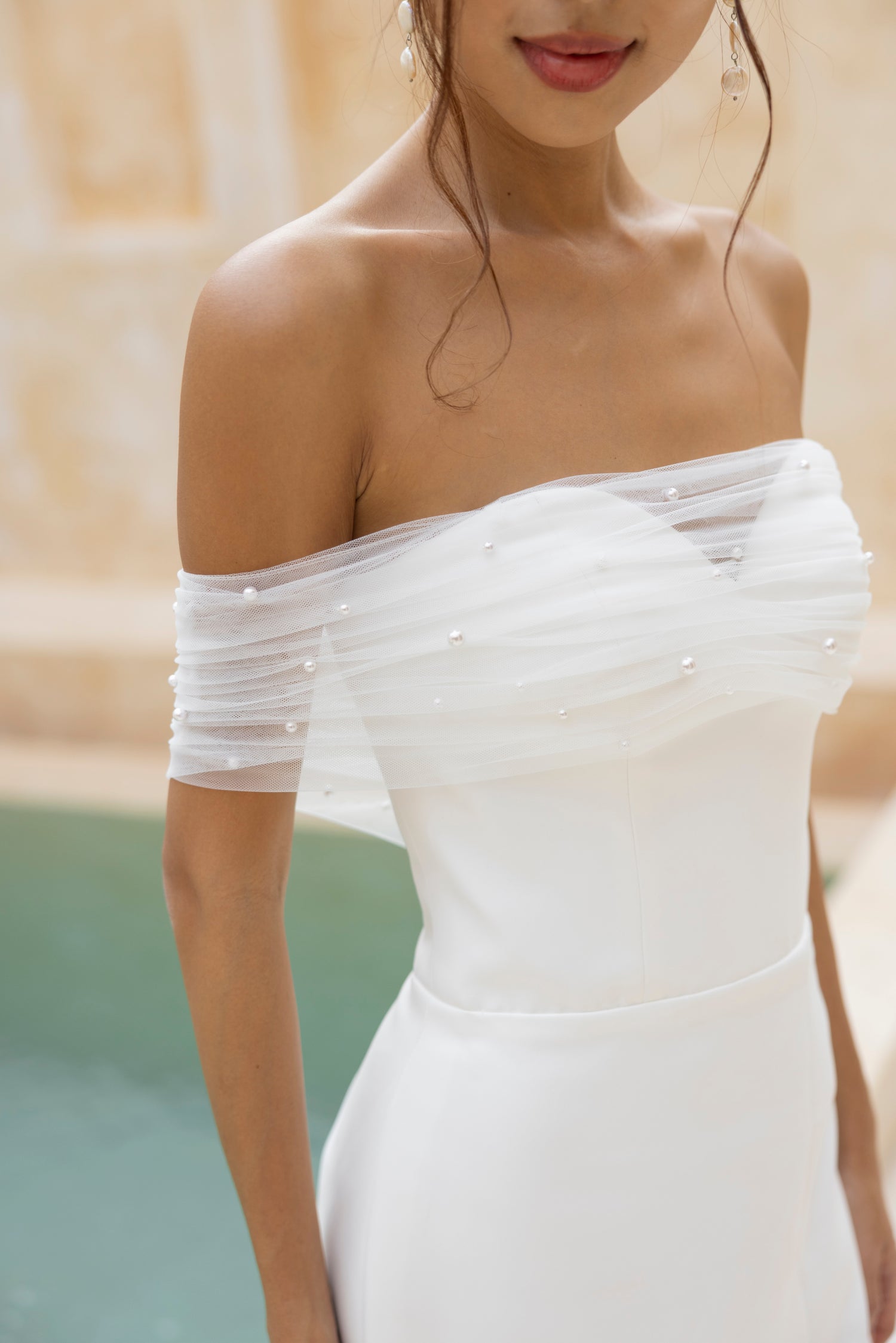 Close up view of the detachable pearl-embellished tulle wrap on the Teagan crepe wedding dress by TheWolfandLily.