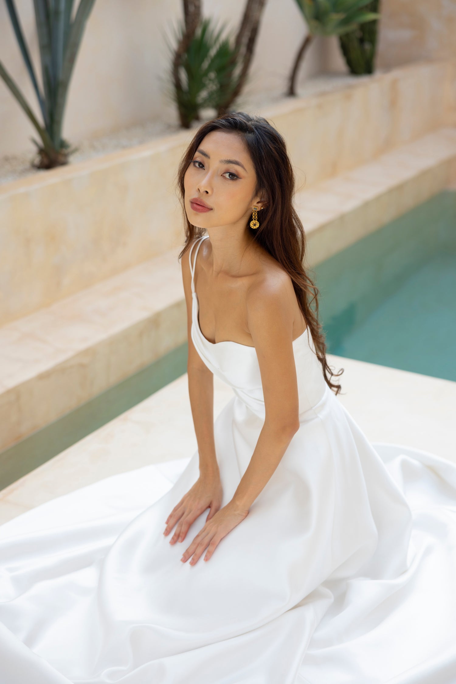 Bride seated in the Sloane wedding dress by TheWolfandLily, showcasing its soft drape and fitted bodice