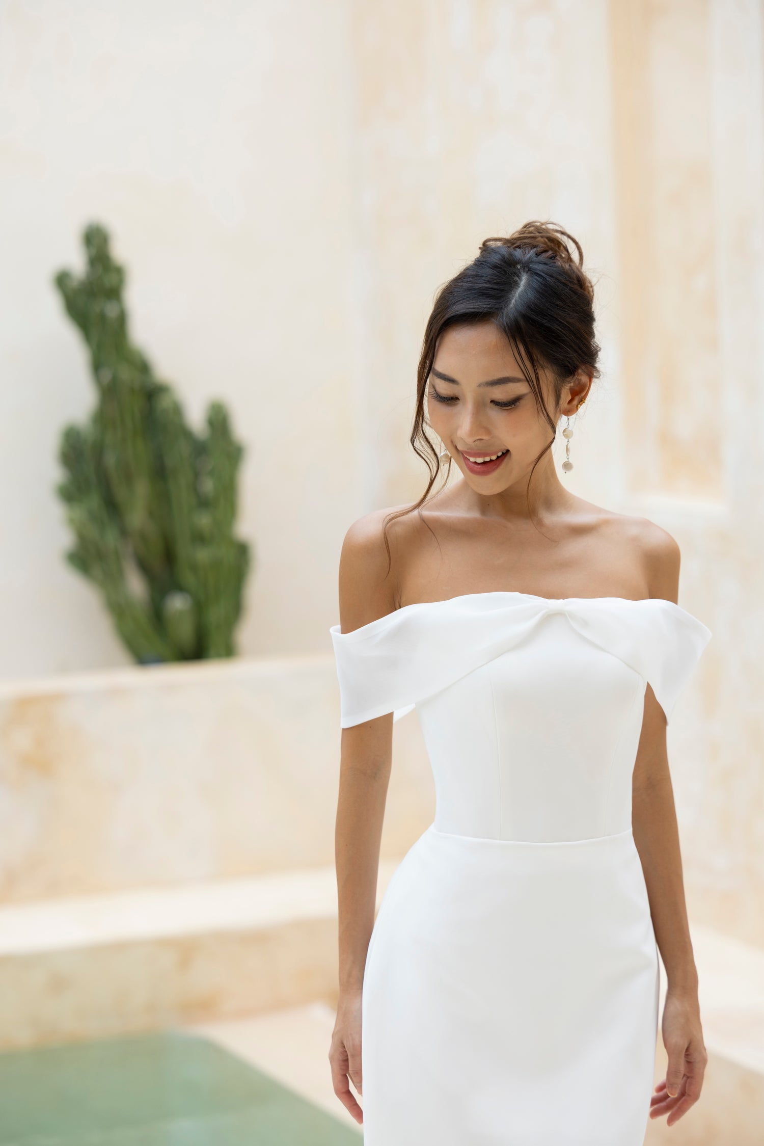 Bride smiling in the Robin gown by TheWolfandLily, off-shoulder neckline with organza bow off shoulder detail