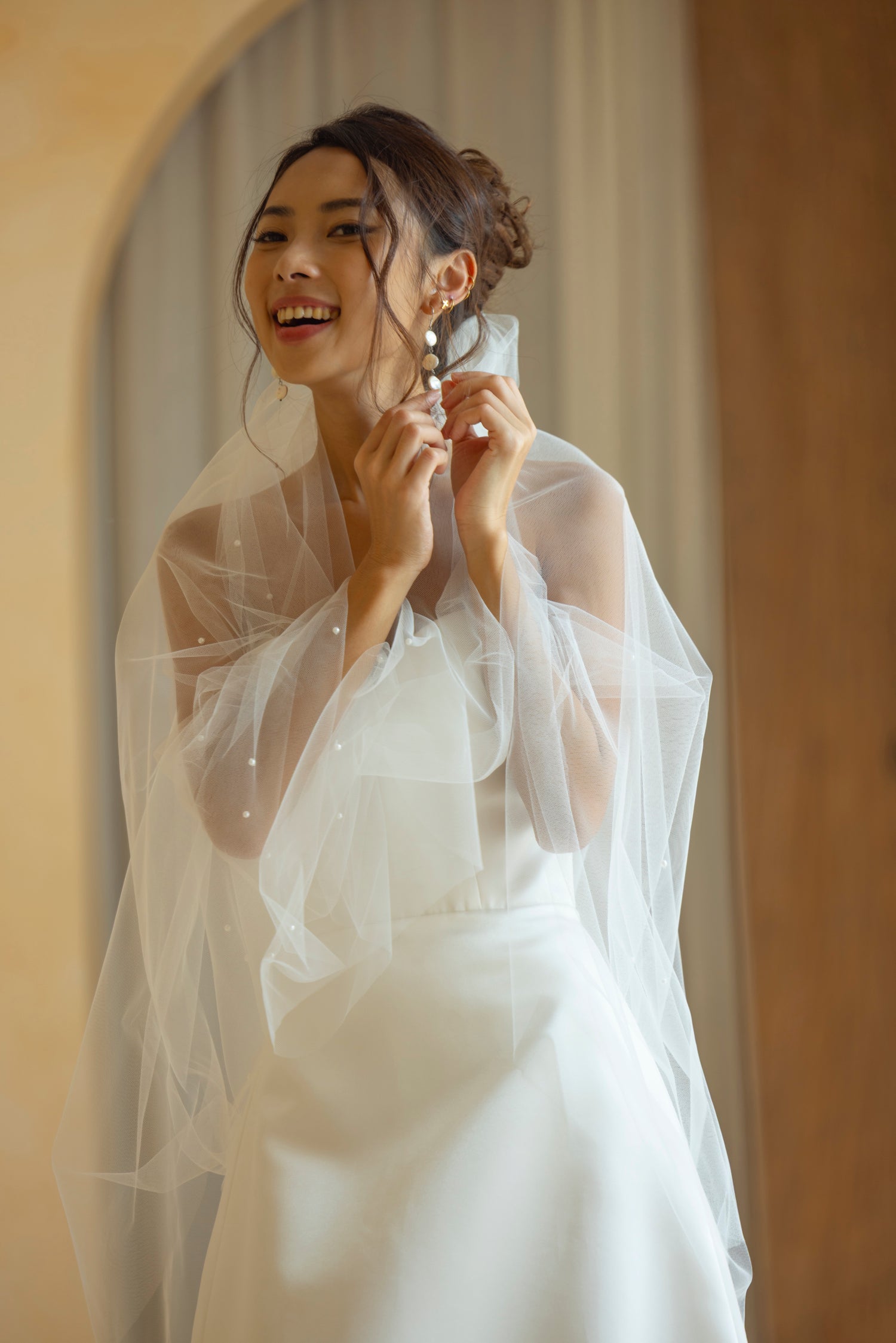Bride in Hally gown styling a minimalist satin bridal gown with veil and earrings by TheWolfandLily